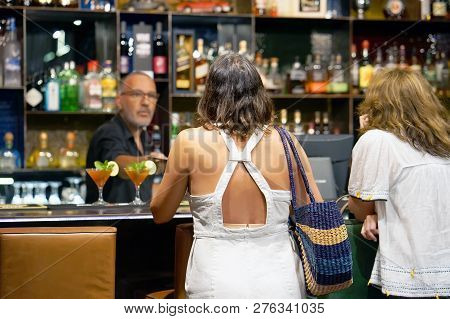 The Barman Gives A Cocktail Two Women The Client Of The Hotel Bar. Fresh Red Cocktail With Grapefrui