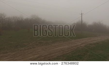 Electricity Transmission Line In Front Of Foggy Forest Near Contryside Road. Shot. Electrical Supply