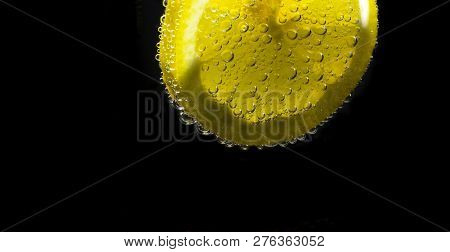 A Slice Of Lemon With Bubbles Isolated On Black Background