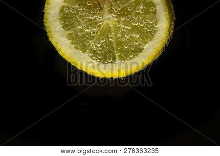 A Slice Of Lemon With Bubbles Isolated On Black Background