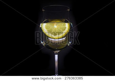 Glass Of Water With A Slice Of Lemon With Bubbles, Isolated On A Black Background.