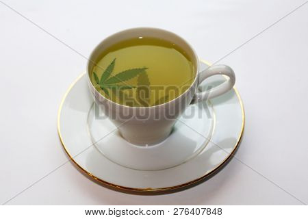 Cannabis Tea. Marijuana Tea. Hemp Tea with a Marijuana Leaf in a white Tea Cup. Isolated on white. Room for text. 