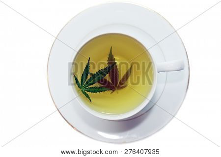 Cannabis Tea. Marijuana Tea. Hemp Tea with a Marijuana Leaf in a white Tea Cup. Isolated on white. Room for text. 