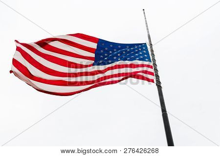 United States Flag Flying At A Half-staff Waving Against Gray Sky