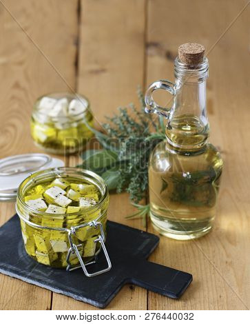 Marinated Feta In A Glass Jar, Spices And Olive Oil On A Wooden Background