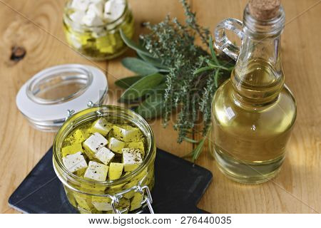 Marinated Feta In A Glass Jar, Spices And Olive Oil On A Wooden Background