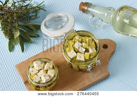 Marinated Feta In A Glass Jar And Spices Against Blue Background