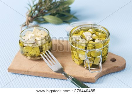 Marinated Feta In A Glass Jar And Spices Against Blue Background