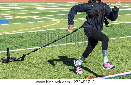 A High School Female Sprinter Is Running While Pulling A Sled With A Weight On It For Resistance Tra