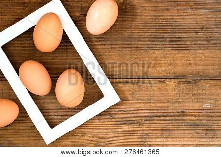 White Diagonal Frame With Three Eggs On The Old Rustic Wooden Brown Background With Copyspace For De