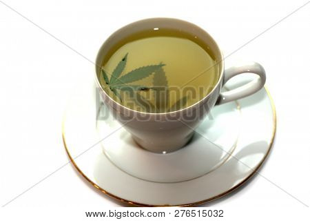 Cannabis Tea. Marijuana Tea. Hemp Tea with a Marijuana Leaf in a white Tea Cup. Isolated on white. Room for text. 