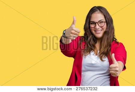 Beautiful plus size young business woman wearing elegant jacket and glasses over isolated background approving doing positive gesture with hand, thumbs up smiling and happy for success. Looking