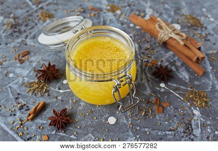 Ghee Oil In A Glass Jar. Spices: Yellow Mustard, Red Mustard, Cinnamon, Anise, Zira Seeds On A Grey 