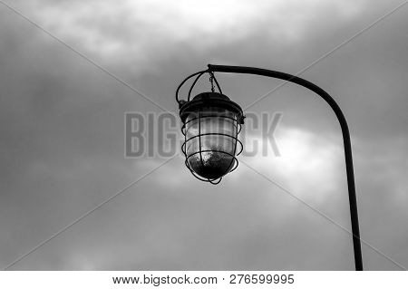 Old Street Lamp On The Background Of A Blocky Sky Suspended On An Iron Rusty Curved Tube