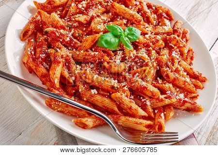 Close-up Of A Portion Of Classic Italian Penne Arrabiata On A White Plate With Basil And Freshly Gra