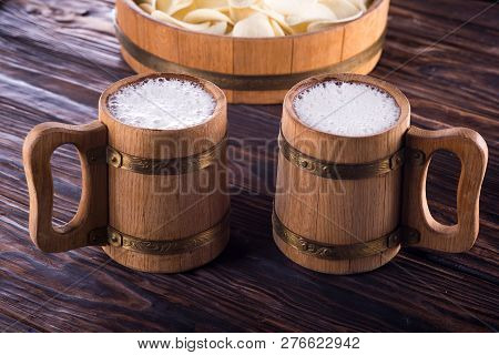 Two Oak Mugs With Beer Inside. On Dark Wooden Background