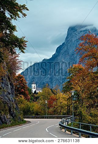 Beautiful Scenic Sunset Over Austrian Alps Lake. Highway Road Infront Of Church On The Rock With Clo
