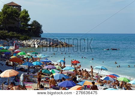PORTONOVO, ANCONA, ITALY - AUGUST 12, 2018: People on the beach on Adriatic sea in hot season. Portonovo, nestled in the green of Conero Park, is famous for its nature and the beauty of its beaches