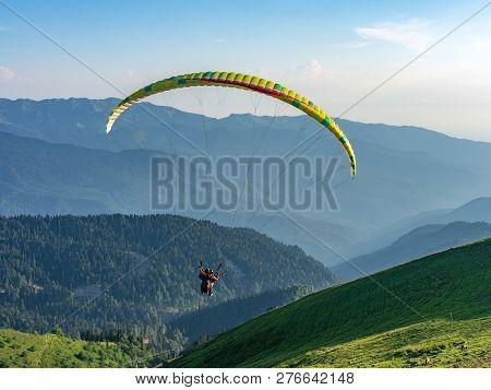 Paraglider In Blue Clear Sky Over The Green Mountain