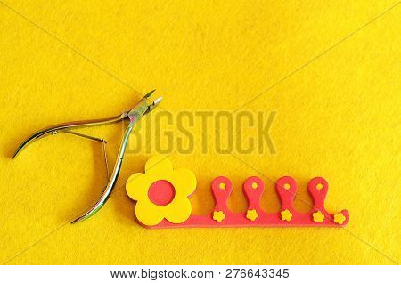 Nail Clipper And Toe Separator On A Yellow Background