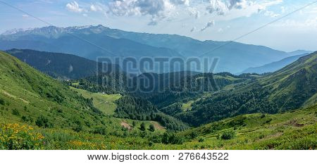 The View From The Height Of A Green Mountain Valley With Residential Buildings Surrounded By High Mo