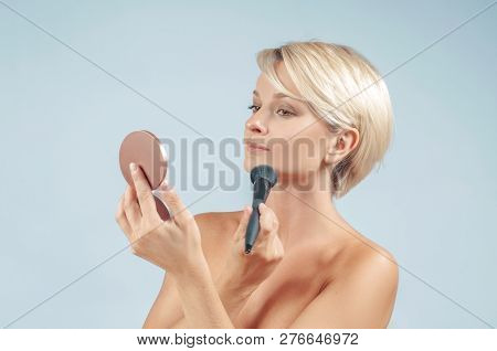 Beautiful Woman Applying Makeup With Powder Brush On The Face Looking At A Mirror