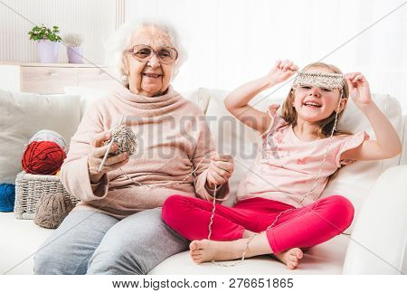 Smiling granddaughter with grandmother kniting together
