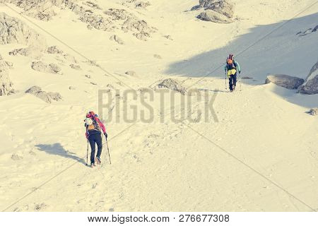 Alpinists Ascending A Snowy Mountain Slope With Crampoons.