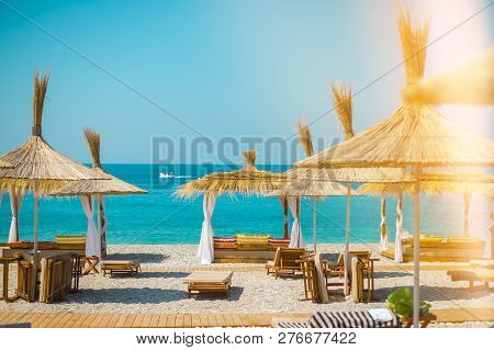 Sunshade Umbrellas And Deckchairs On The Beautiful Beach In Himara, Turquoise Water Of Ionian Sea In