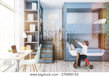 Little Boy In Interior Of Modern Bedroom With White Walls, Wooden Floor, Gray And Wooden Bunk Bed, A