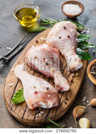 Chicken legs with spices and salt  ready for cooking on cutting board.