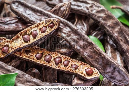 Carob pods and carob beans on the wooden table.