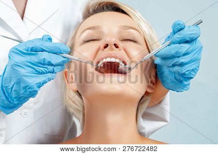 Dentist Examining A Patient's Teeth In The Dentis.