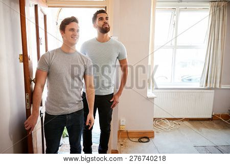Excited Male Couple Opening Front Door Of New Home