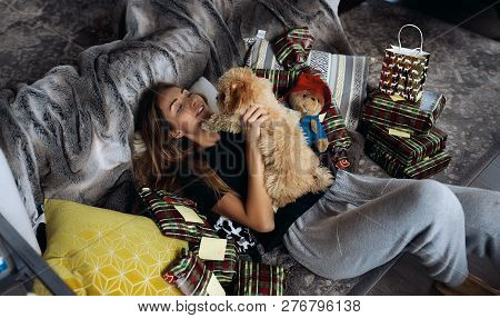 Winter Picture Of Pretty Blonde Woman In Black Shirt And Grey Pants. Lying On A Couch With Little Cu