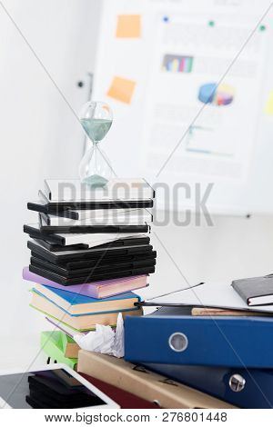 Hourglass On Stack Of Dvds And Folders In Light Business Office