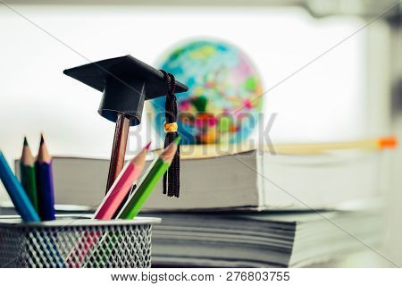 Education Graduate Study Concept: Black Graduation Hat On Pencils, Blur Of Europe Earth World Globe 
