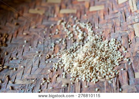 A Pile Of Unpeeled And Peeled Rice In Woven Bowl