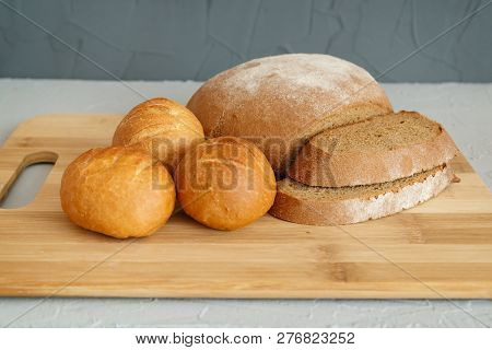 Rye Bread And Scones On Wooden Board On Grey Background