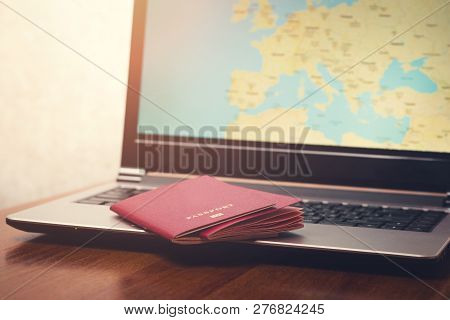 Two International Passport On The Laptop Surface. The Display Shows A Map Of Europe