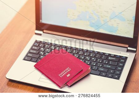 Two International Passport On The Laptop Surface. The Display Shows A Map Of Europe