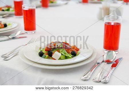 Greek Salad And Juice On A White Table In A Restaurant