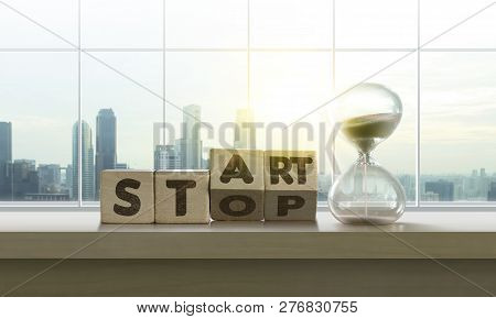Wooden Blocks With The Word Start-stop And Sand Clock On Table With Panoramic City Skyline Backgroun