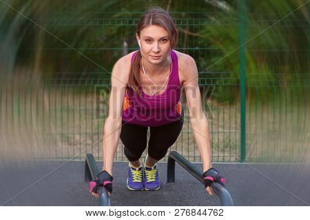 Young Caucasian Woman Workouts On The Park Sports Ground, In A Plank Position, Bright Sportswear. Wh