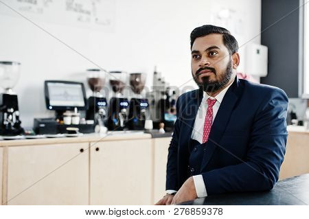 Stylish Beard Indian Business Man On Suit Sitting At Cafe.