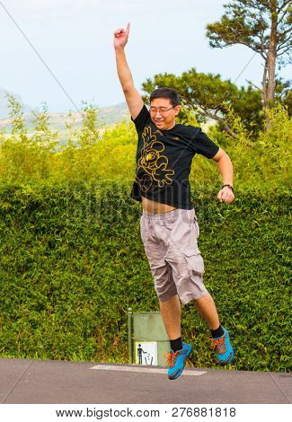 Curepipe / Mauritius Island - 28. October, 2018: Unidentified Chinese tourist jumping and exercising in city park. Asian people traveling around the world.