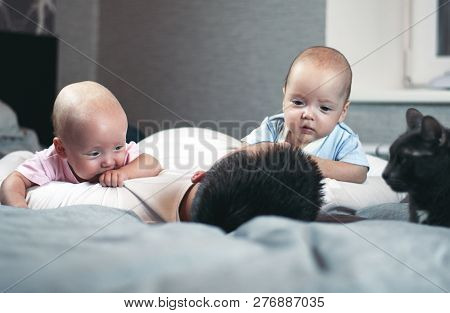 Young Father With His Newborn Twins Lying In Bed. Selective Focus