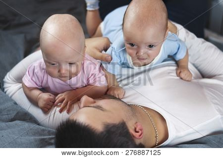 Young Father With His Newborn Twins Lying In Bed. Selective Focus