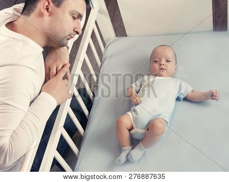 Young Dad Is Tired Of Putting A Small Child To Bed. Dad And Son Fatherly Care Concept. Selective Foc