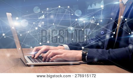 Businessman typing on laptop with linked reports charts grapghs around